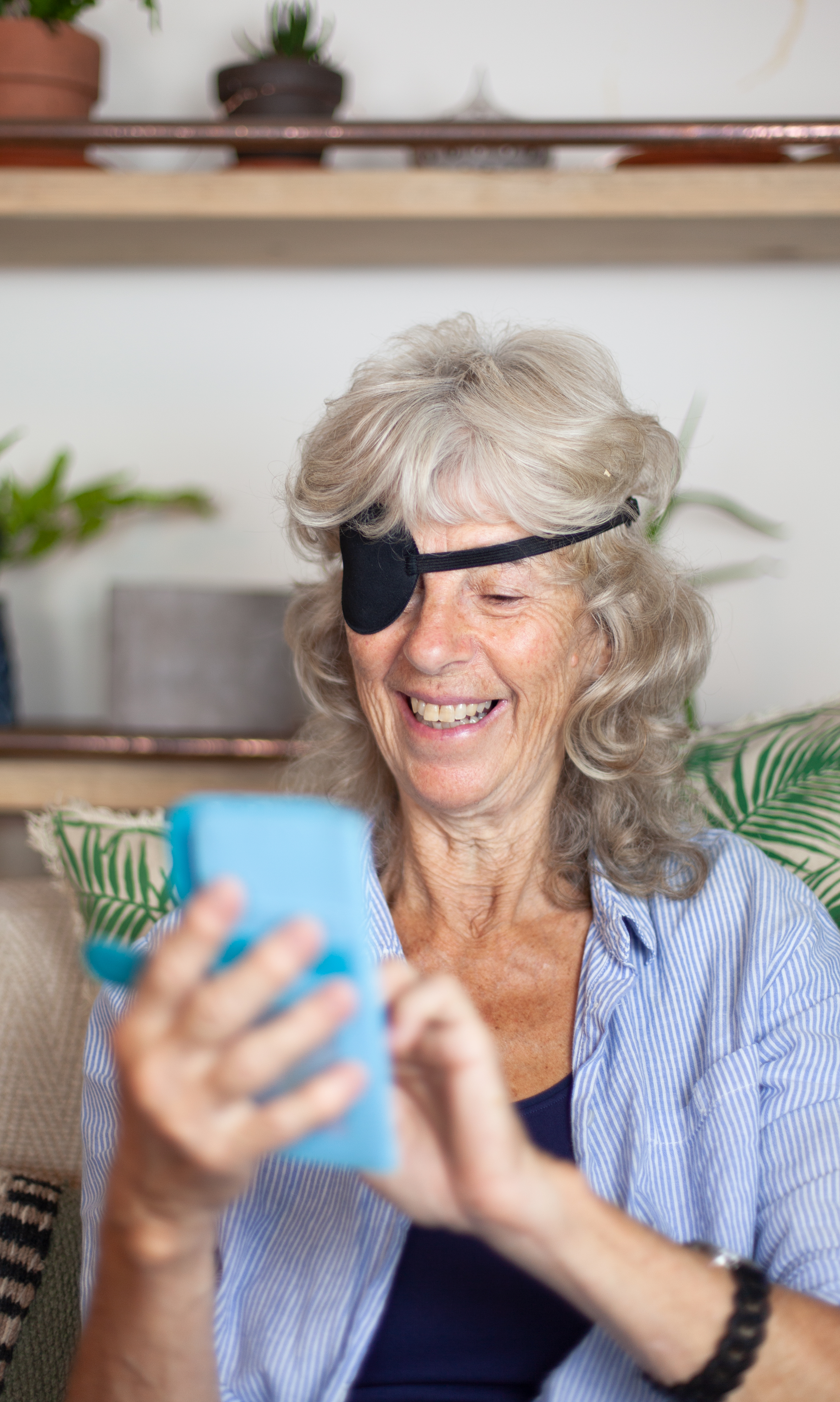 Elderly woman with eye patch smiling on phone