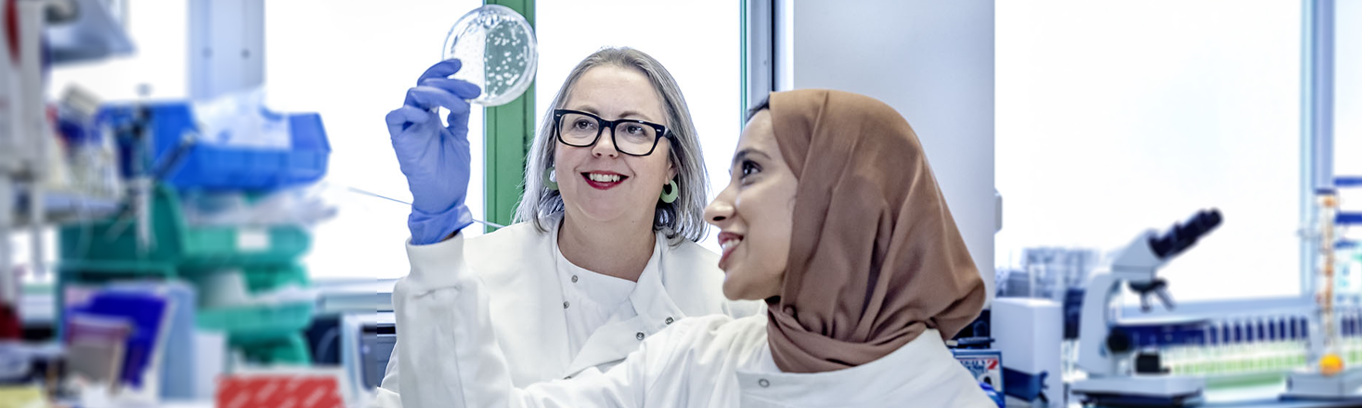 Dr Carr and colleague in the lab, holding a petri dish and looking at it's contents
