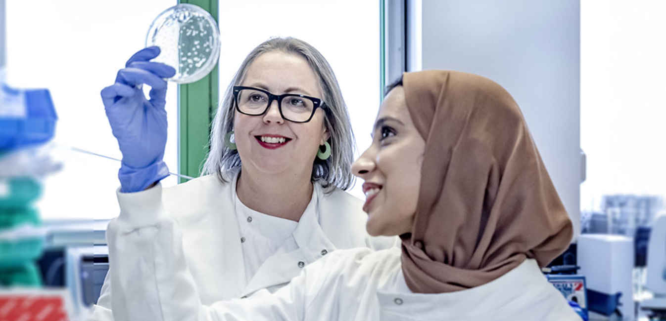 Dr Carr and colleague in the lab, holding a petri dish and looking at it's contents