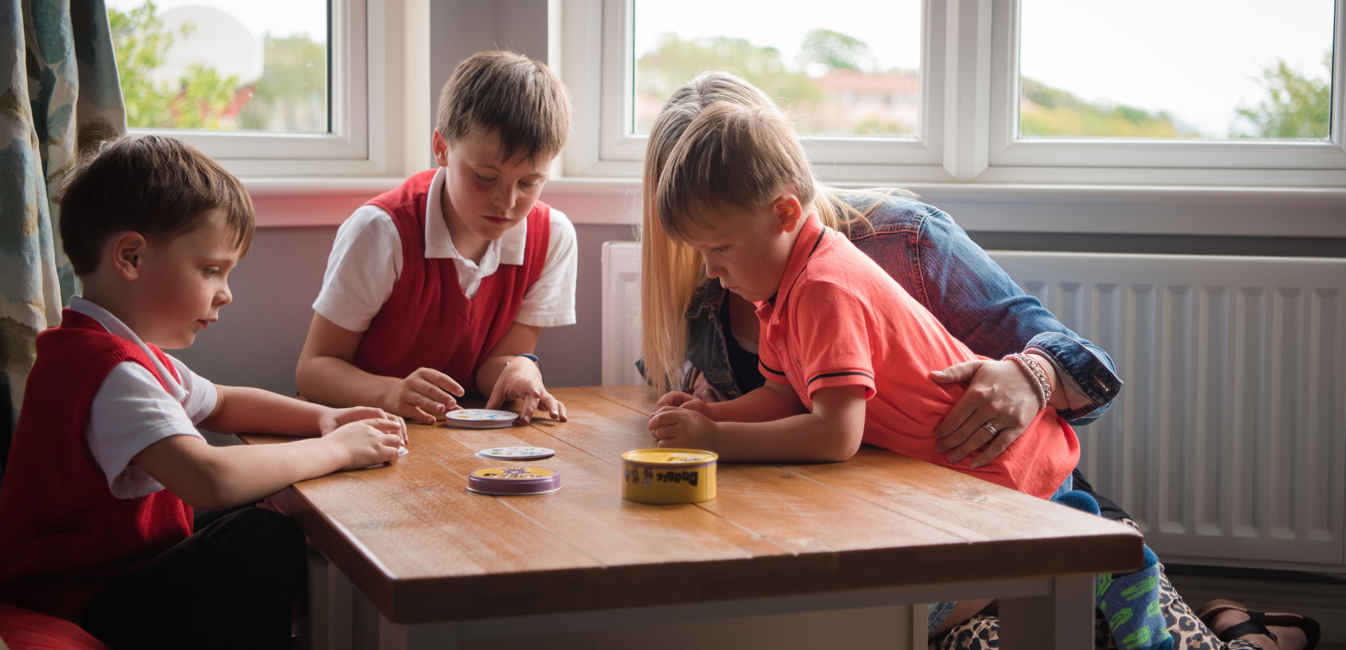 Kelly and the three boys playing at the table