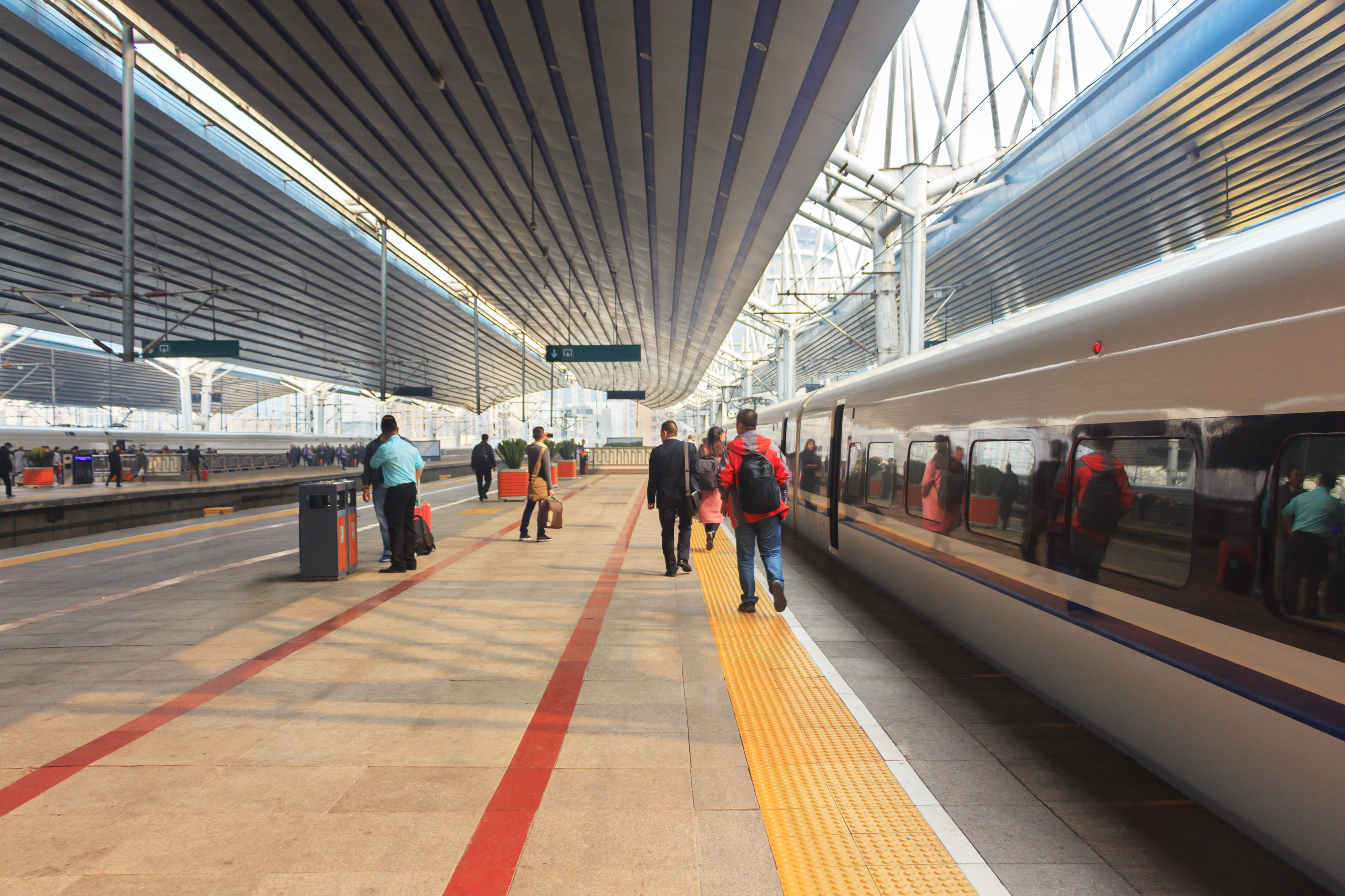 Train platform with people walking as they prepare to board the train.