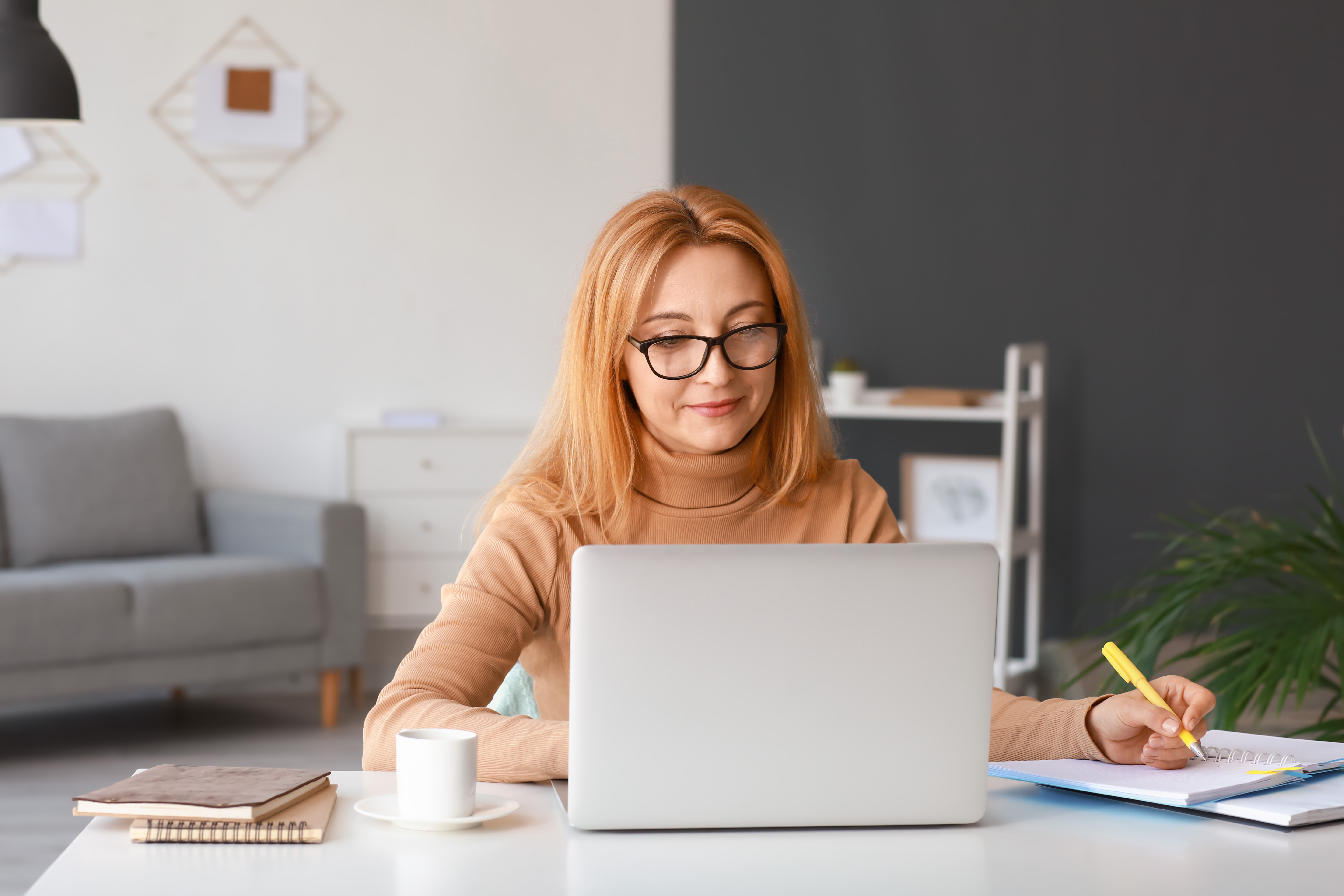 Woman on laptop at home making notes