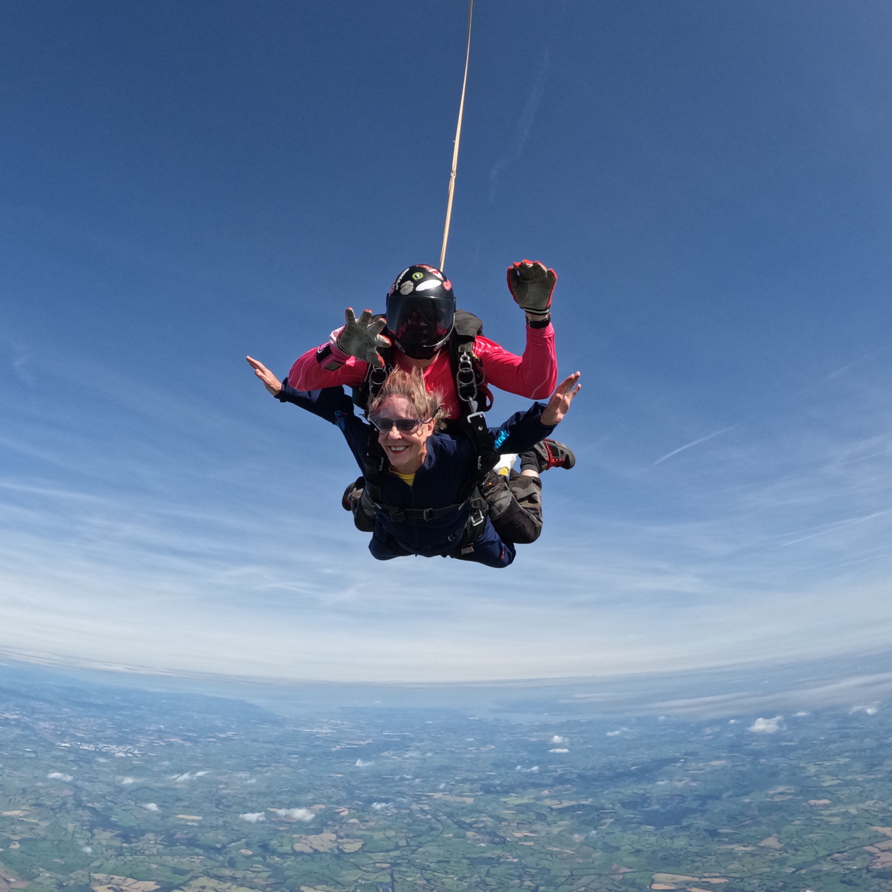 Janet Burton in mid air as she falls from the sky in a tandem skydive. Her instructor is strapped on top.