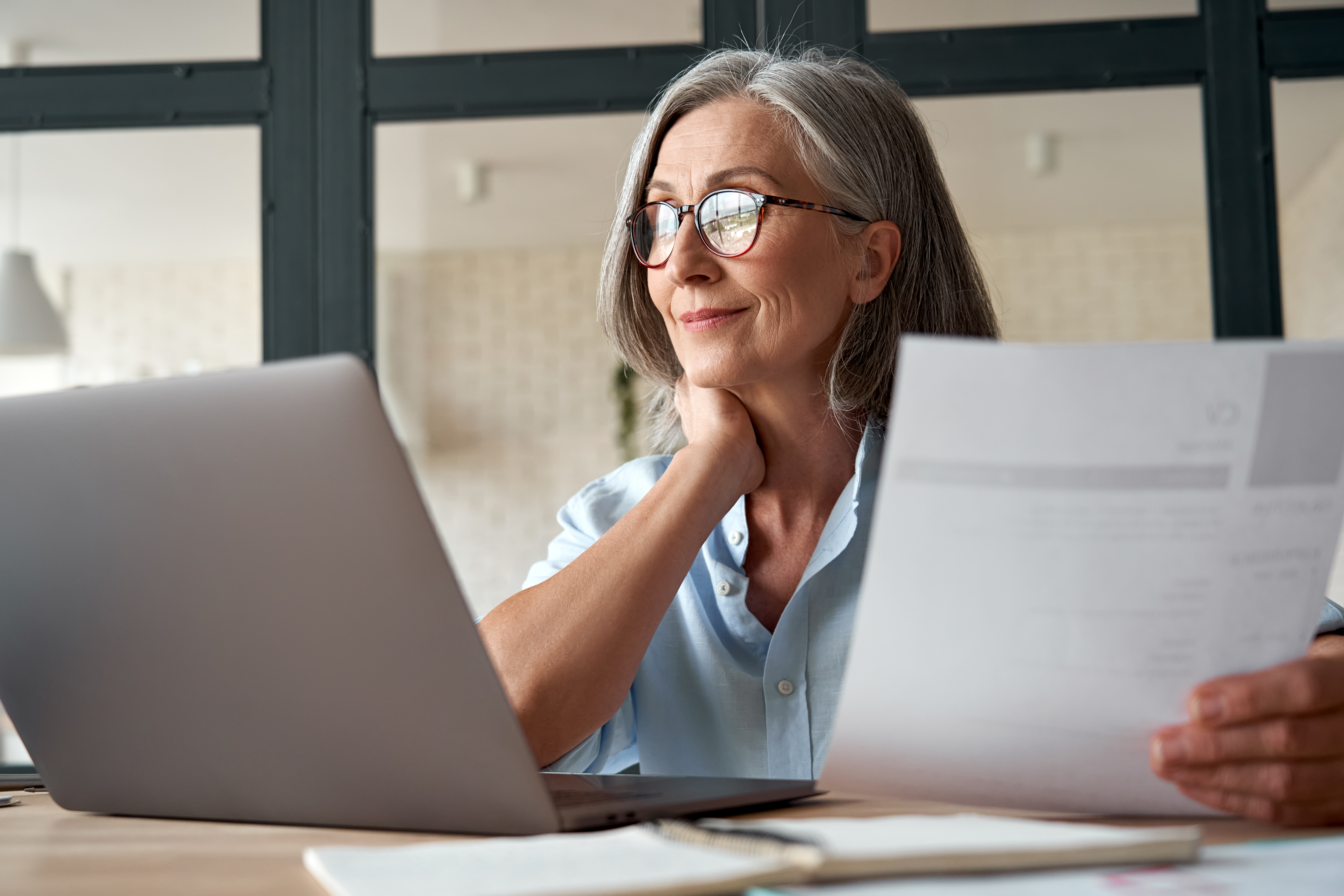 Lady on laptop with papers in hand