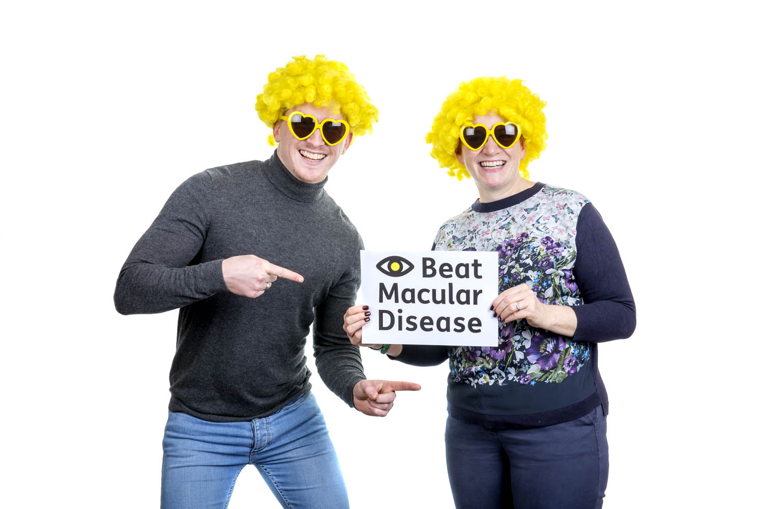 Macular Week 2022 man and woman with sign in Macular Society wigs and glasses