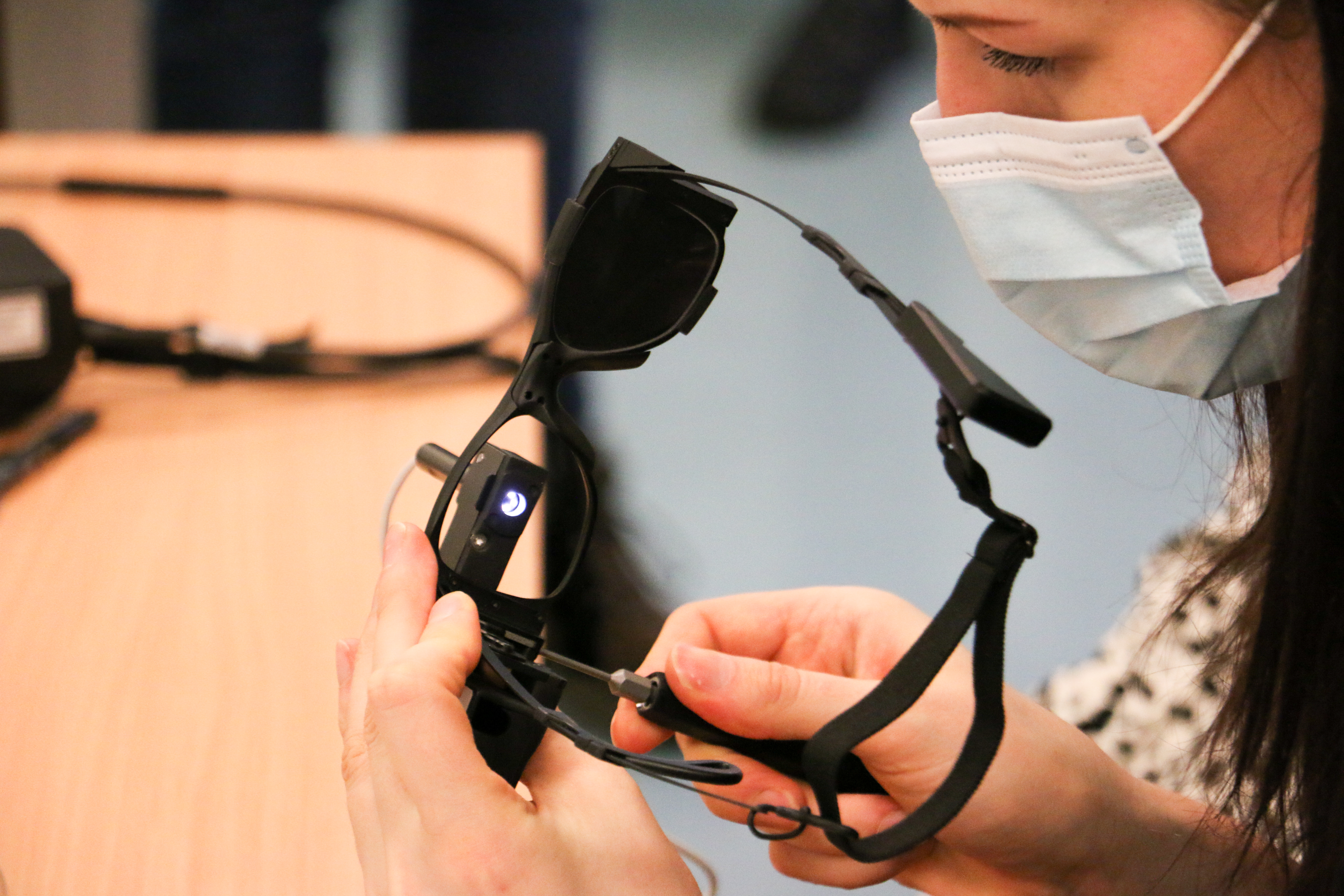 A woman fitting a pair of the black bionic glasses used as part of the PRIMA System