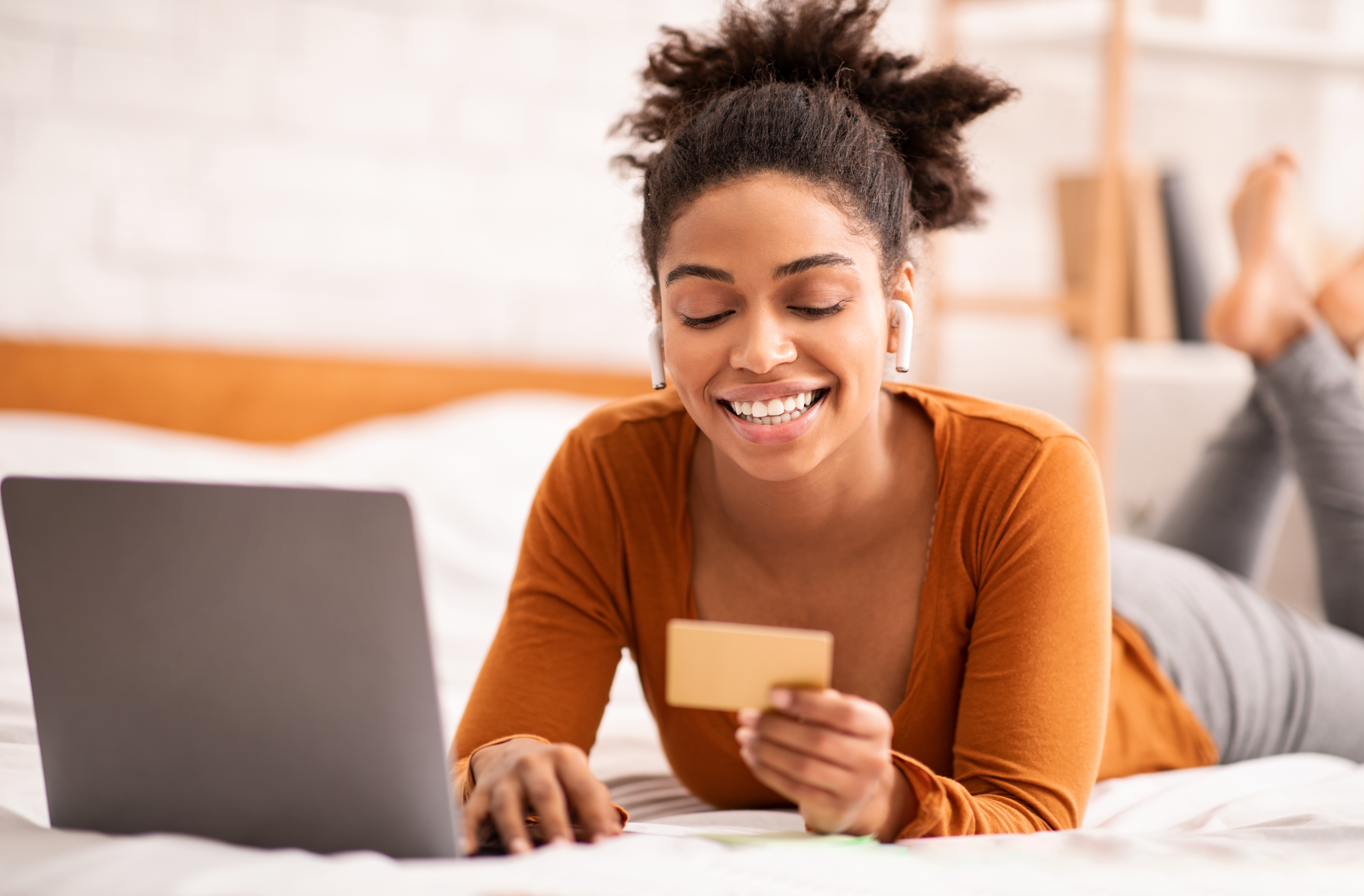 Woman on bed with laptop and credit card