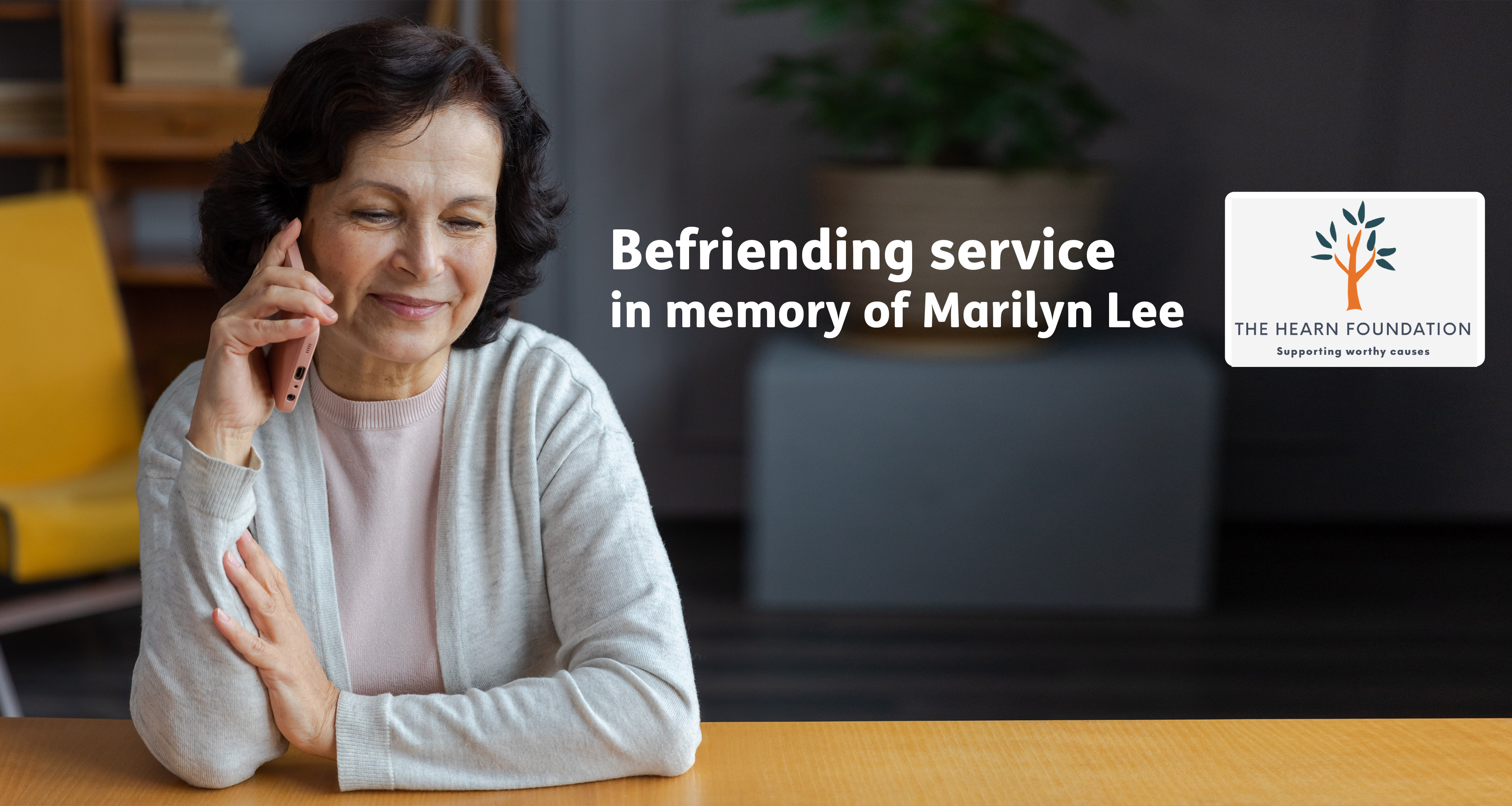 Befriending service user smiling on the phone with text 'Befriending in memory of Marilyn Lee'