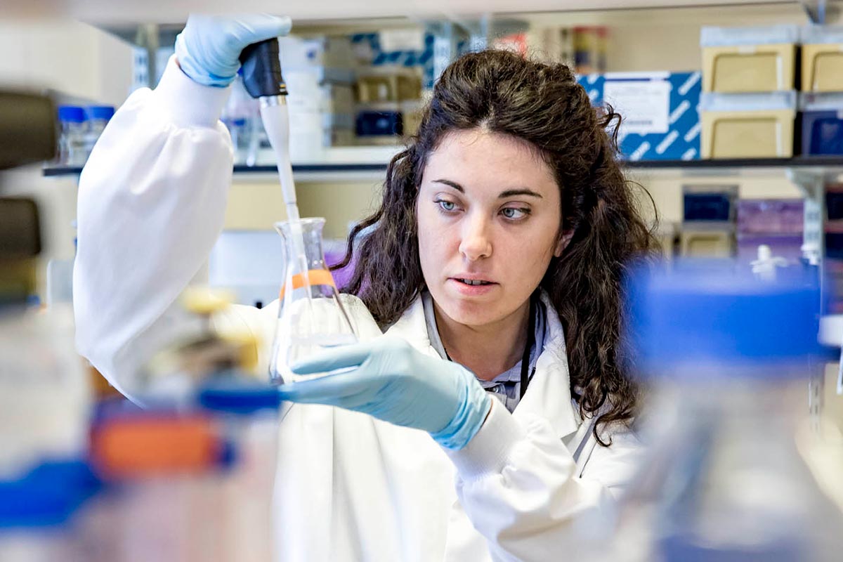 Scientist holding pipette and glass beaker