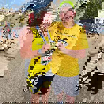 Becky and Richard with their arms around each other and smiling as they hold up Becky's London Marathon medal.