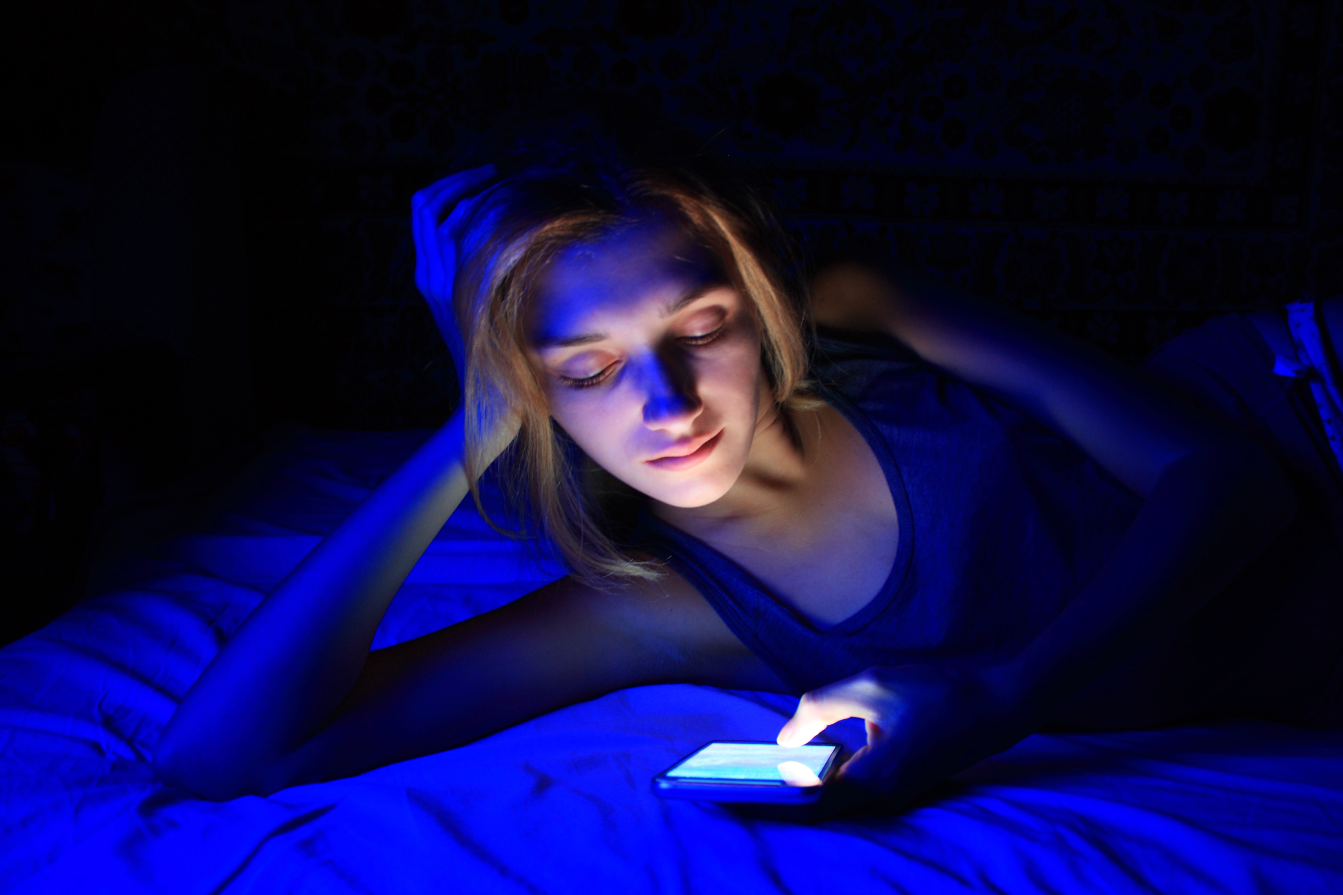A woman looking at her phone in the dark with blue light