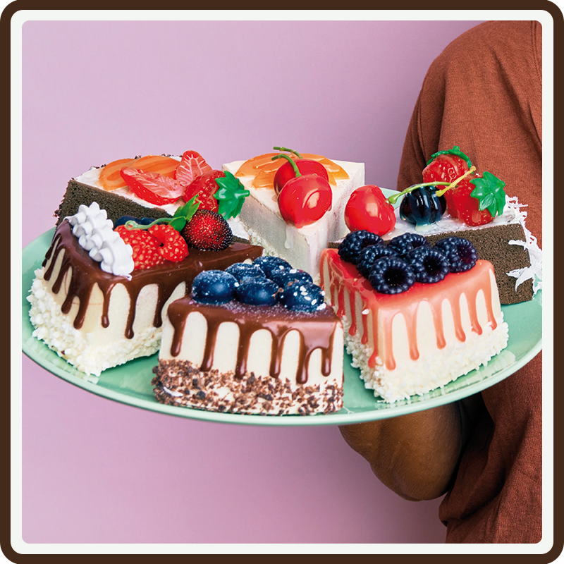 A blue plate with a variety of decorated cake slices with a pink backdrop