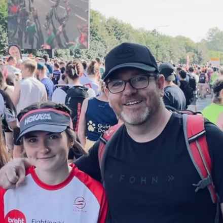 Izzy stands next to her dad Trevor, his arm around her, having completed a previous running challenge.