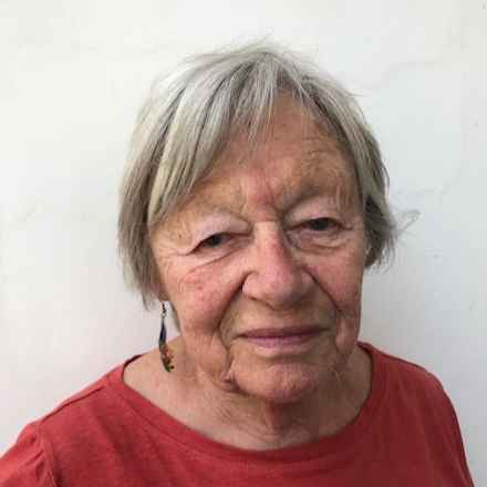 Headshot of Sheila, grinning while wearing a red top.