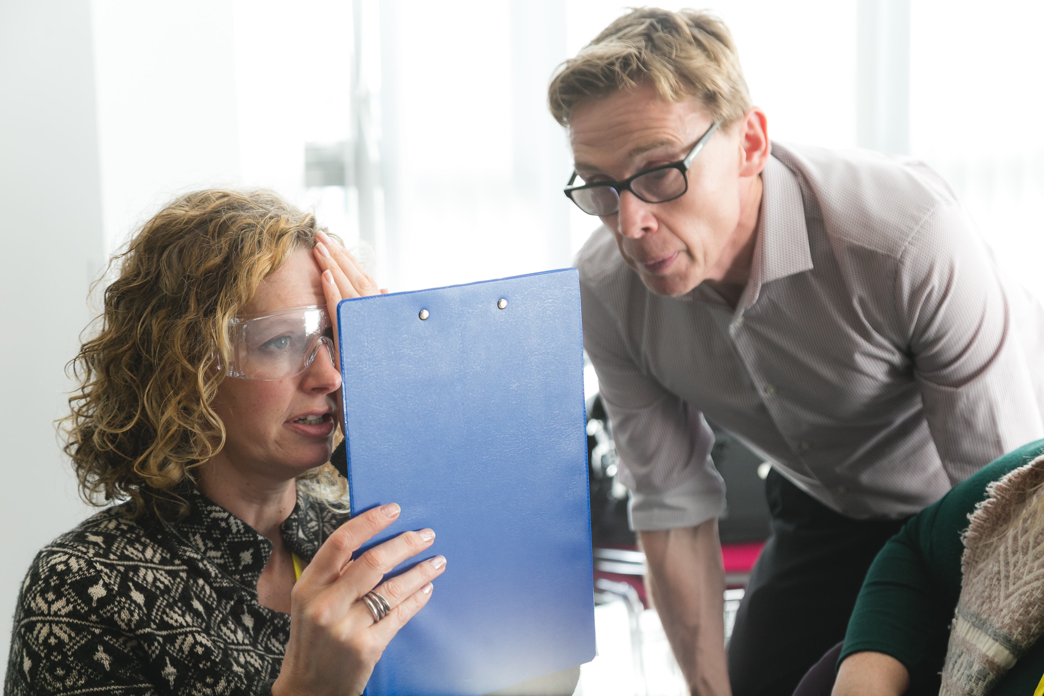 Skills for Seeing - woman wearing glasses with clip board, covering one eye, while a man oversees 