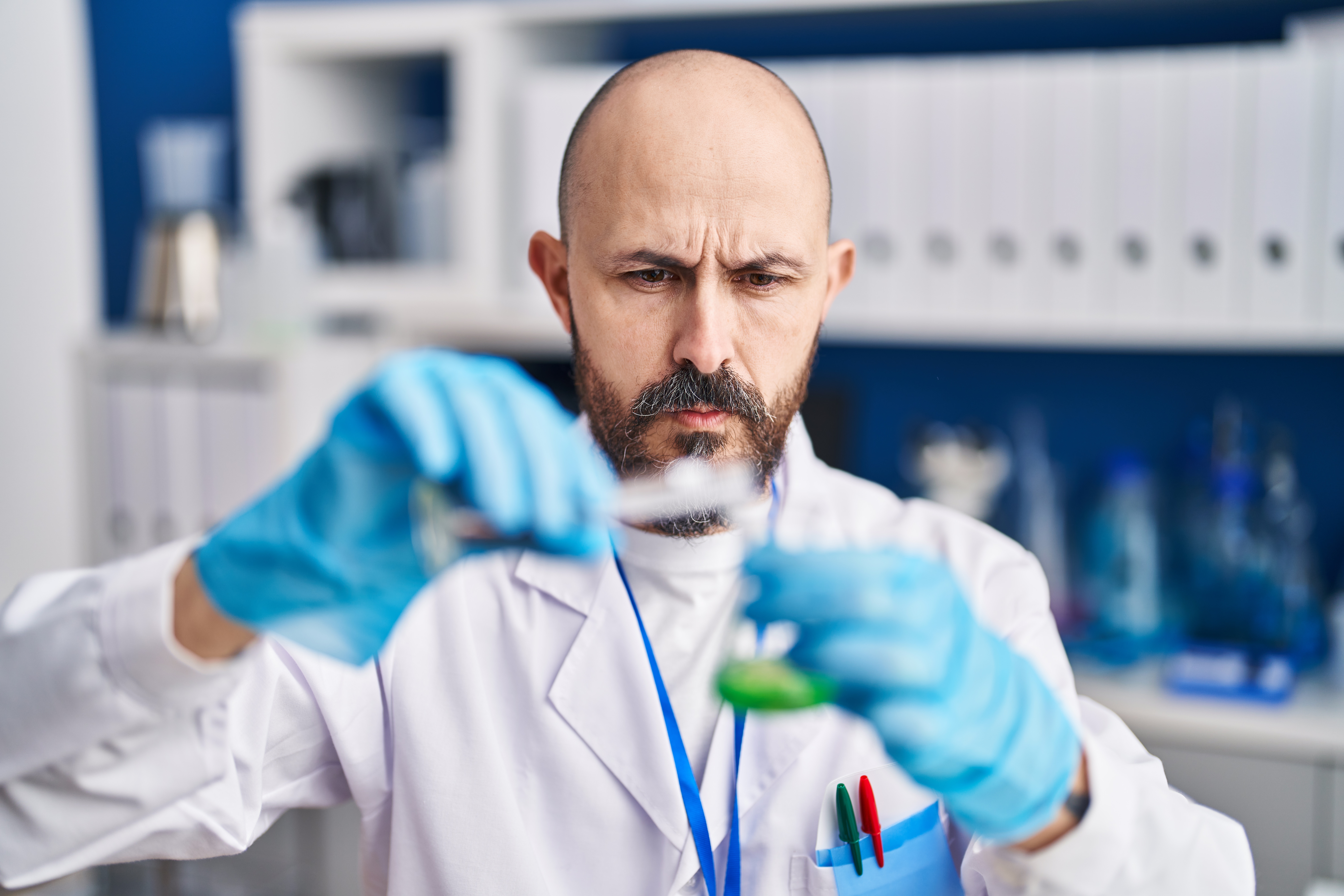 Researcher concentrating and pouring liquid into a small vial