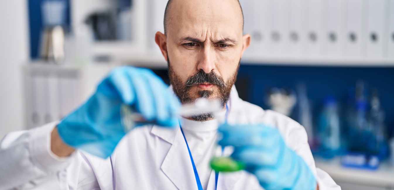 Researcher concentrating and pouring liquid into a small vial